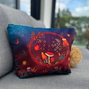 Kosmetiktasche Zauberwelt mit wunderschönem Waldmotiv auf einer Couch