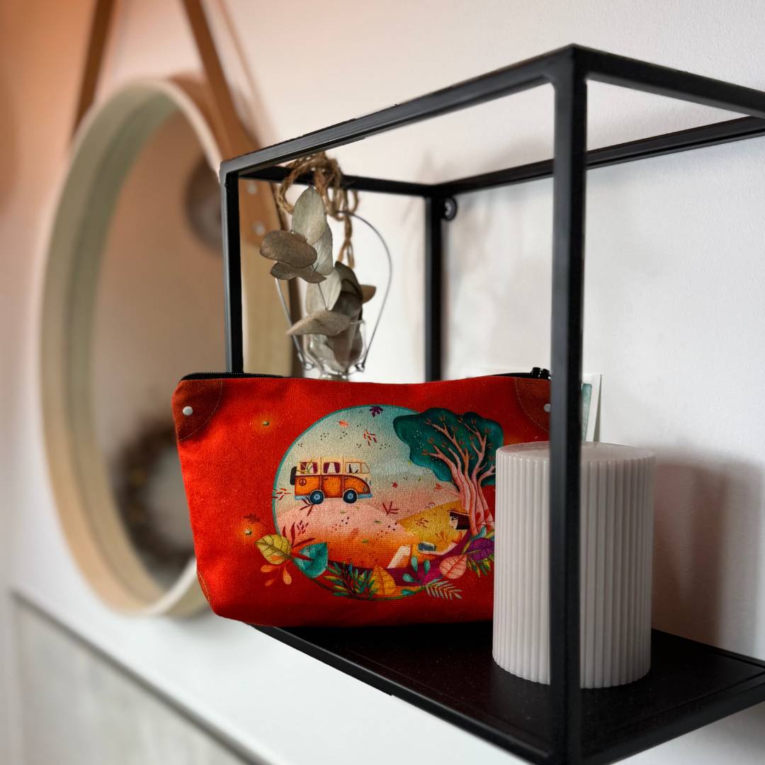 Schminktasche Freiheit Indien, Wandregal vor einer Kerze mit Motiv einer Frau in der Natur an einen Baum gelehnt, dazu ein kleiner Bus