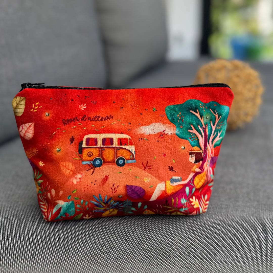 Schminktasche Freiheit steht auf einer Couch und zeigt warme Farben, Pflanzen und eine Frau mit Buch in der Hand an einen Baum gelehnt